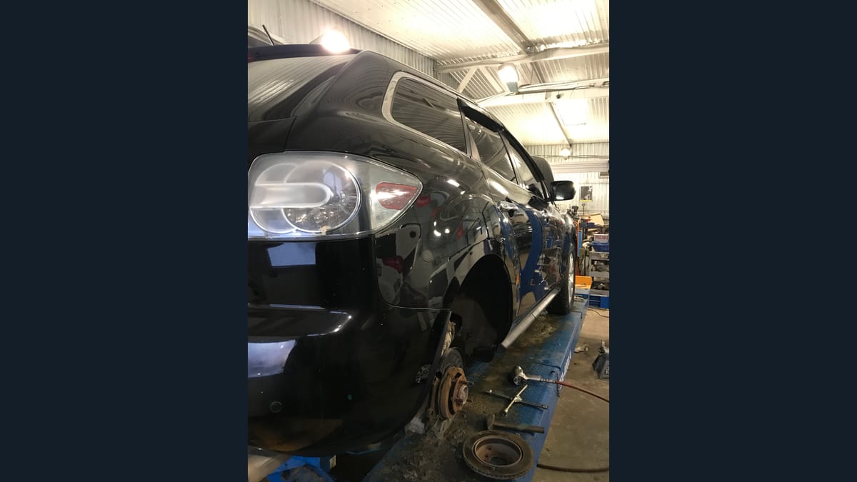 Автомобиль со снятым колесом на подъёмнике в цеху